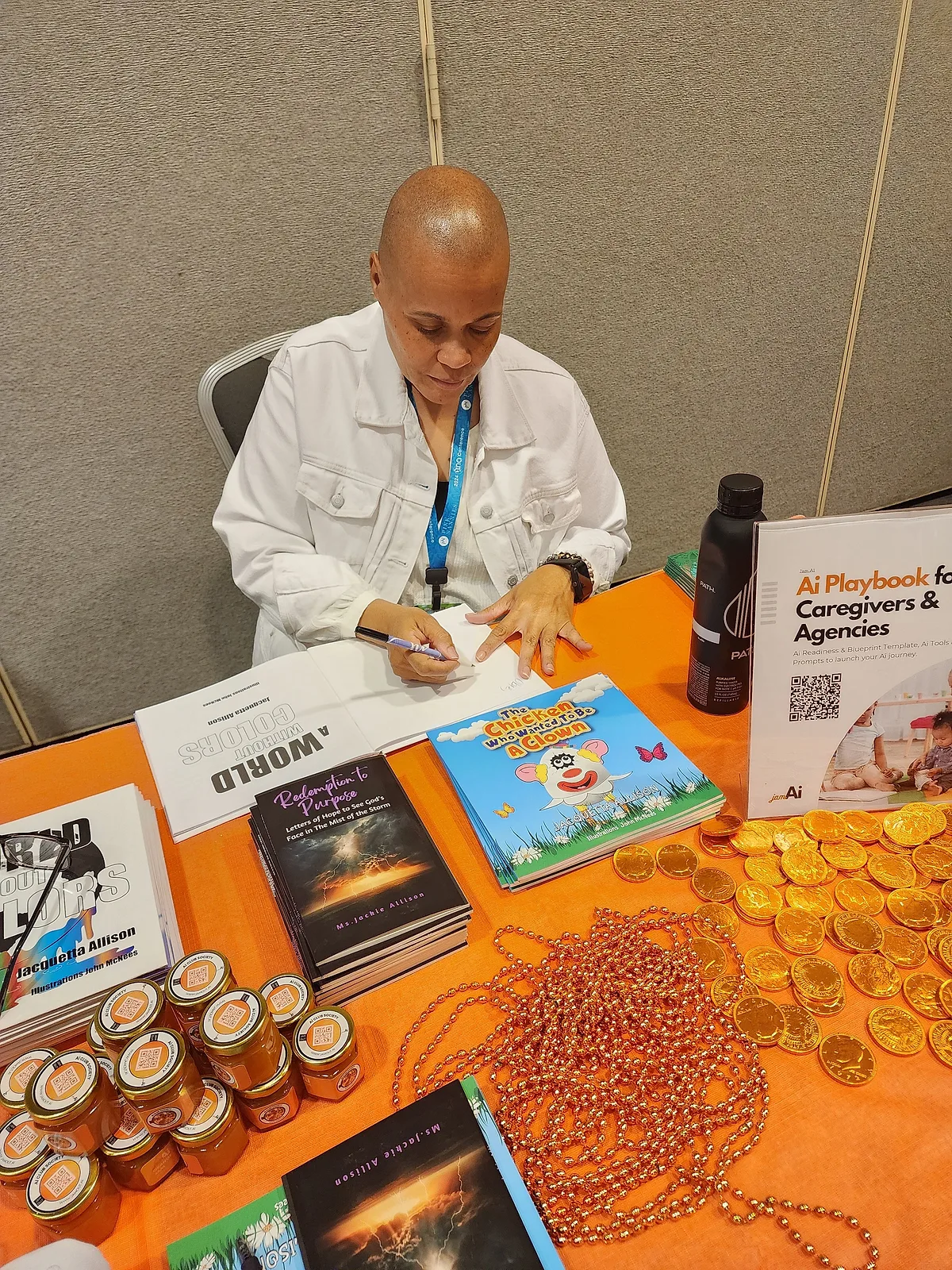Jackie Allison signing a book at a table spread with copies of her books.