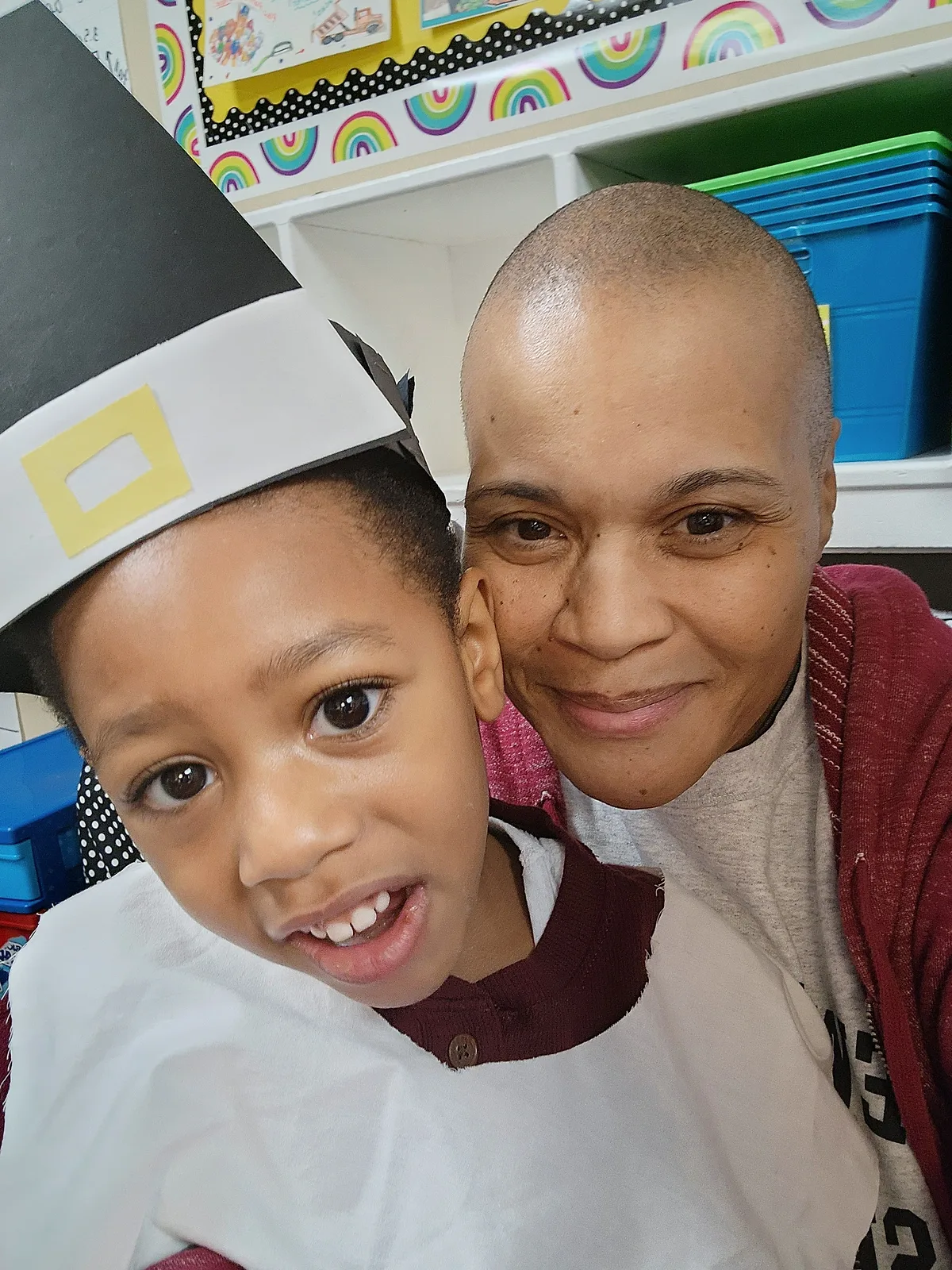 Jackie Allison smiling in a classroom selfie with a young child.
